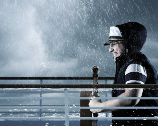man steering ship through storm